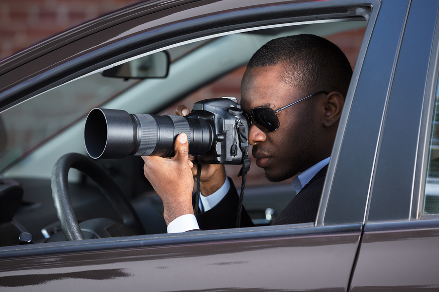 Private Detective Sitting Inside Car Photographing With SLR Camera
